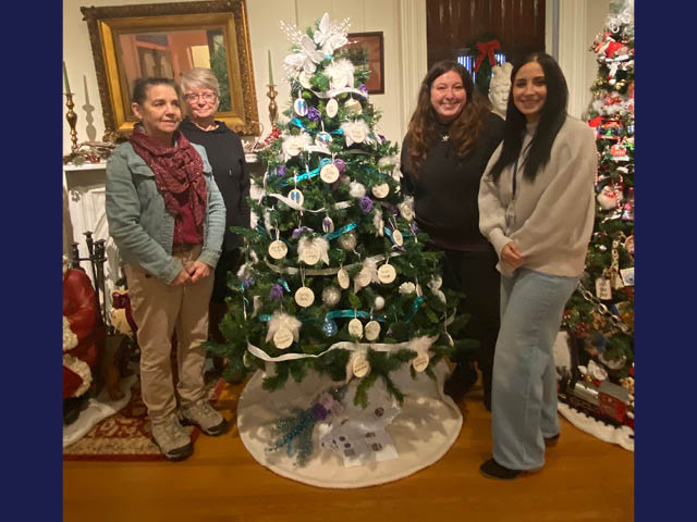 Four women standing around a Christmas tree known as the remembrance tree