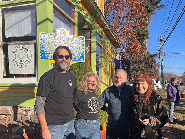 Two couples standing in front of the historical marker at the historic Glass Factory Store building