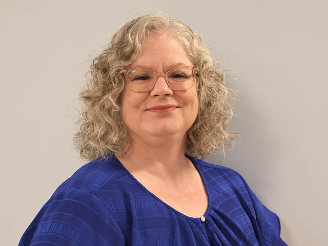 Virginia Bough, a white woman with curly platinum blonde hair in a blue shirt