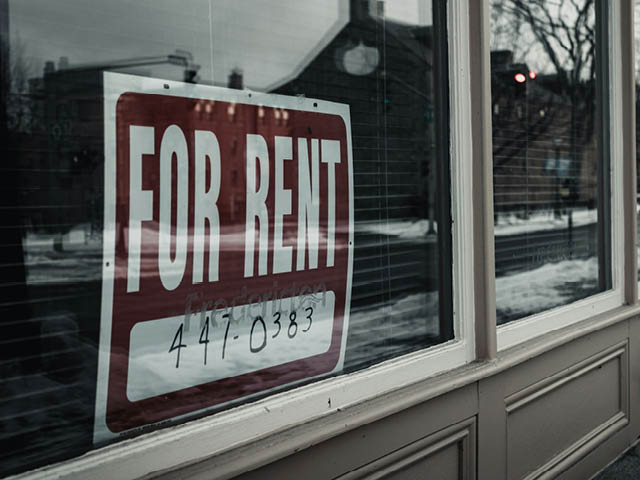 A photo showing a for rent sign in a window with a phone number listed below