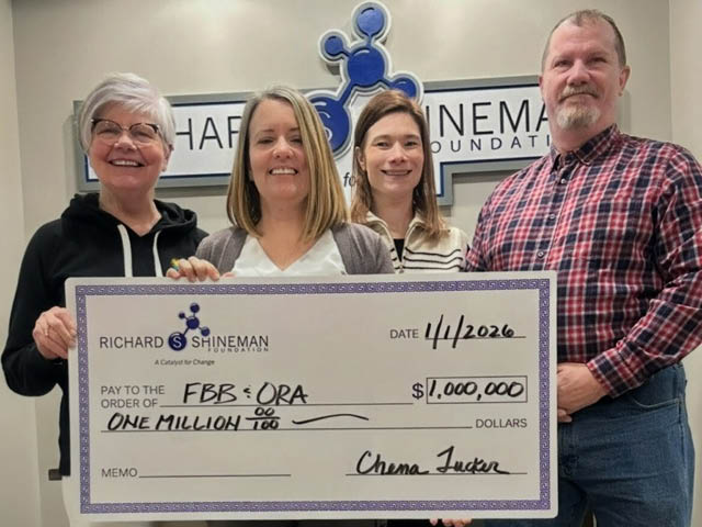 Four people standing and holding up a presentation check from Shineman Foundation to the FBB and ORA