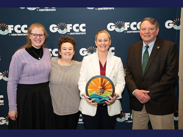 Three women and one man stand in front of a GOFCC background