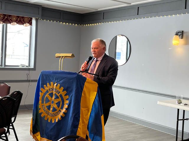 Mayor Rice at a podium that is draped in a Rotary banner