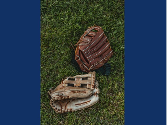 two worn ball gloves laying in bright green grass