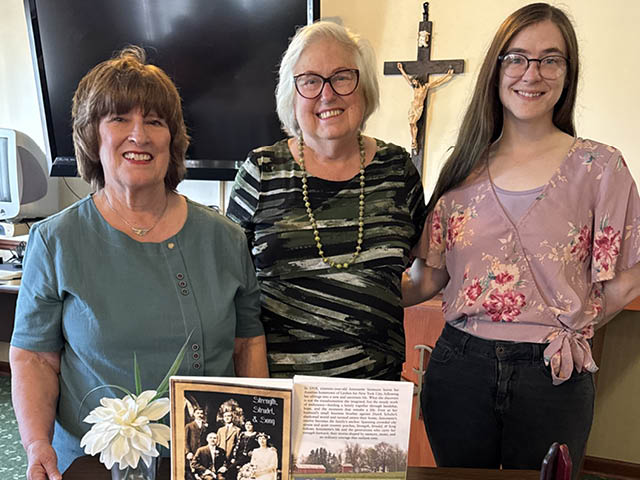 Group photo of Ingerson, Hutchinson, and Leibl in front of a table with Hutchinson's book