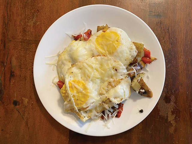 A plate with Southwest Breakfast on it: eggs, cheese, veggies, and potatoes