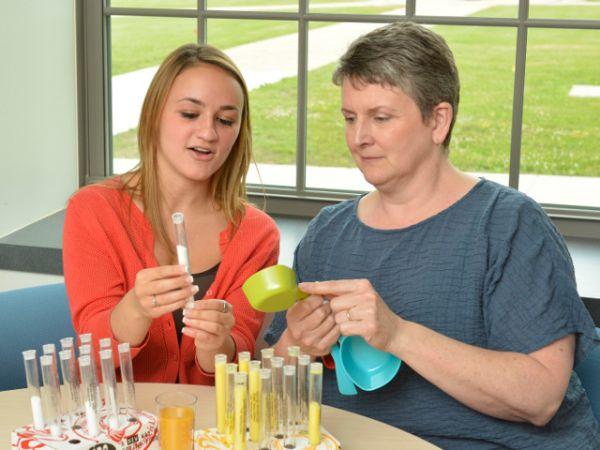 Nutritional display -- SUNY Oswego has added a new minor in nutrition to broaden future employment and graduate school opportunities for students in majors such as wellness management, biology, psychology and more. Here junior Brianna Favata (left) examines a prop that represents the sugar content in an orange drink, amid some of the tools Sandra Bargainnier (right), chair of health promotion and wellness, demonstrated as visual aids for conveying information to classes in the new minor.