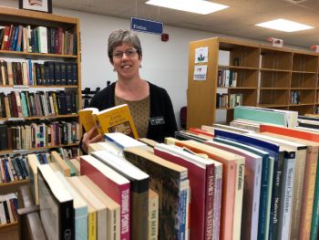 Finding books homes -- Sarah Weisman, director of SUNY Oswego&#039;s Penfield Library, looks over some of the selections that will be available for the library&#039;s book sale from 11 a.m. to 3 p.m. on Friday, Oct. 26, and Saturday, Oct. 27.